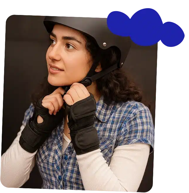 A young woman wearing a checked shirt, black helmet, and wrist guards adjusts her helmet strap while looking up and smiling. A blue cloud graphic in the top right hints at the fun spirit of About Navan Adventure Centre.