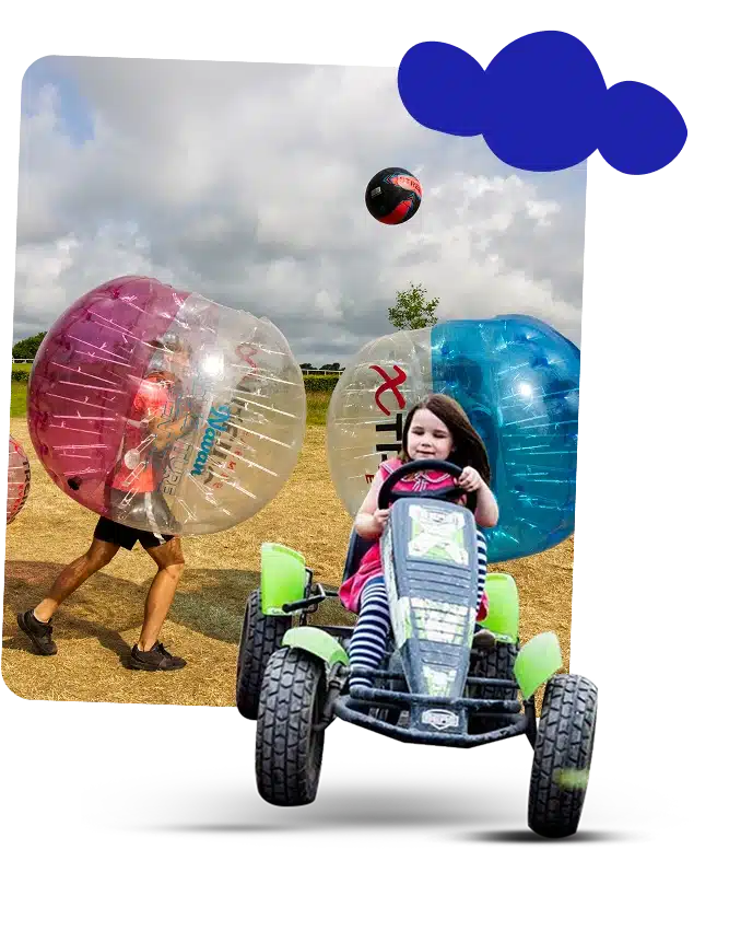 A young girl in a go-kart smiles in the foreground at Navan Adventure Centre, whilst two people in large inflatable bumper balls play on grass behind her under a cloudy sky. A ball is mid-air above them, and blue paint shapes cover part of the sky.